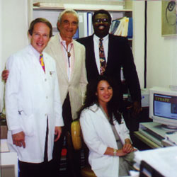 Joseph J. Kaufman, M.D., Emeritus Professor of Surgery/Urology at UCLA, visits USRF in 1992. With Professor Kaufman are Erlinda D. Shery (seated), who was founding research coordinator at USRF; Mannan Reese, Health Science Associate at Merck & Co.